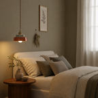 Terracotta hand-painted ceramic pendant light glowing beside an upholstered bed