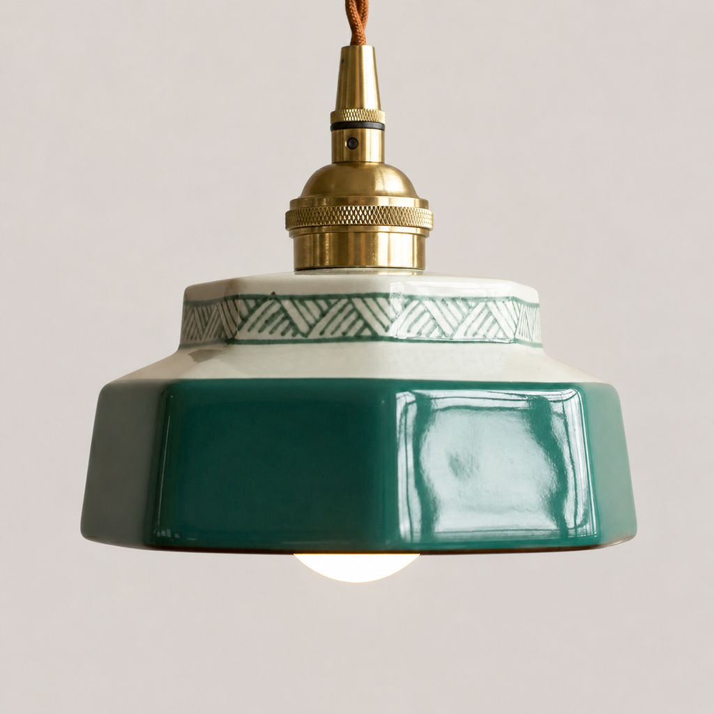 Close detail of a blue-green hand-painted ceramic pendant light with aged brass hardware