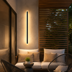 Black linear outdoor wall light casting warm light across a covered patio