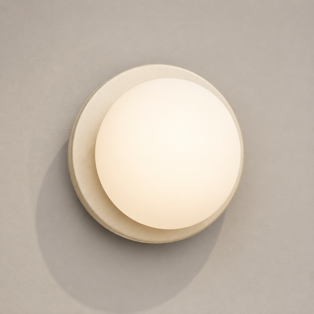 Detail view of a beige Nordic glass globe wall sconce against pale taupe plaster
