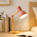 Pink wooden desk lamp casting warm light across a bedroom desk.