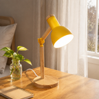 Yellow wooden desk lamp glowing on a sunny window-side workspace.