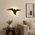 Black origami bird LED wall sconce glowing above an American sofa