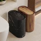 Black marble and wood grain oval trash cans beside a modern bathroom vanity