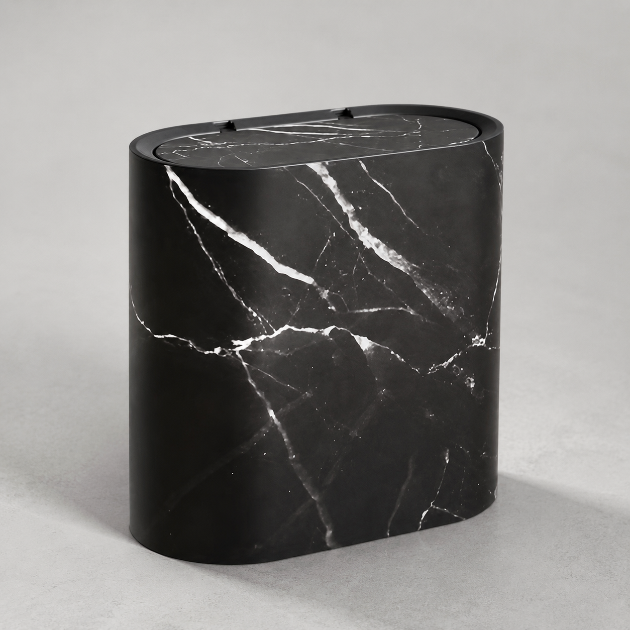 Black marble oval trash can on a neutral gray studio background