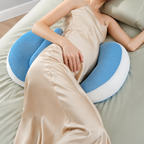 Blue pregnancy pillow supporting both sides of a sleeper on muted green bedding