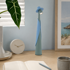 Blue and green rechargeable LED hat lamp on a light wood desk.