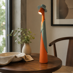 Orange and green rechargeable LED hat lamp on a round walnut side table.