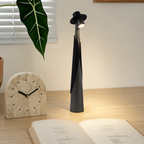 Deep grey rechargeable LED hat lamp glowing on a pale oak desk.