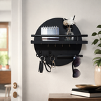 Black round wooden key holder with shelf and hooks on a bright entryway wall.