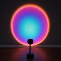 Black sunset projector lamp casting a multicolor circular halo on a dark wall