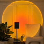 Black sunset projector lamp casting a large amber halo behind a boucle chair