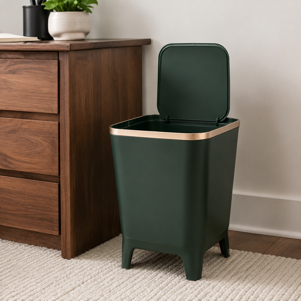 Deep green trash can with its flip-top lid open beside a walnut cabinet in a home office.