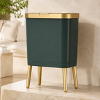 Deep green trash can with elevated legs in a warm limestone studio scene.