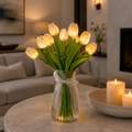 Glowing white LED tulip bouquet in a clear ribbed glass vase on a stone table