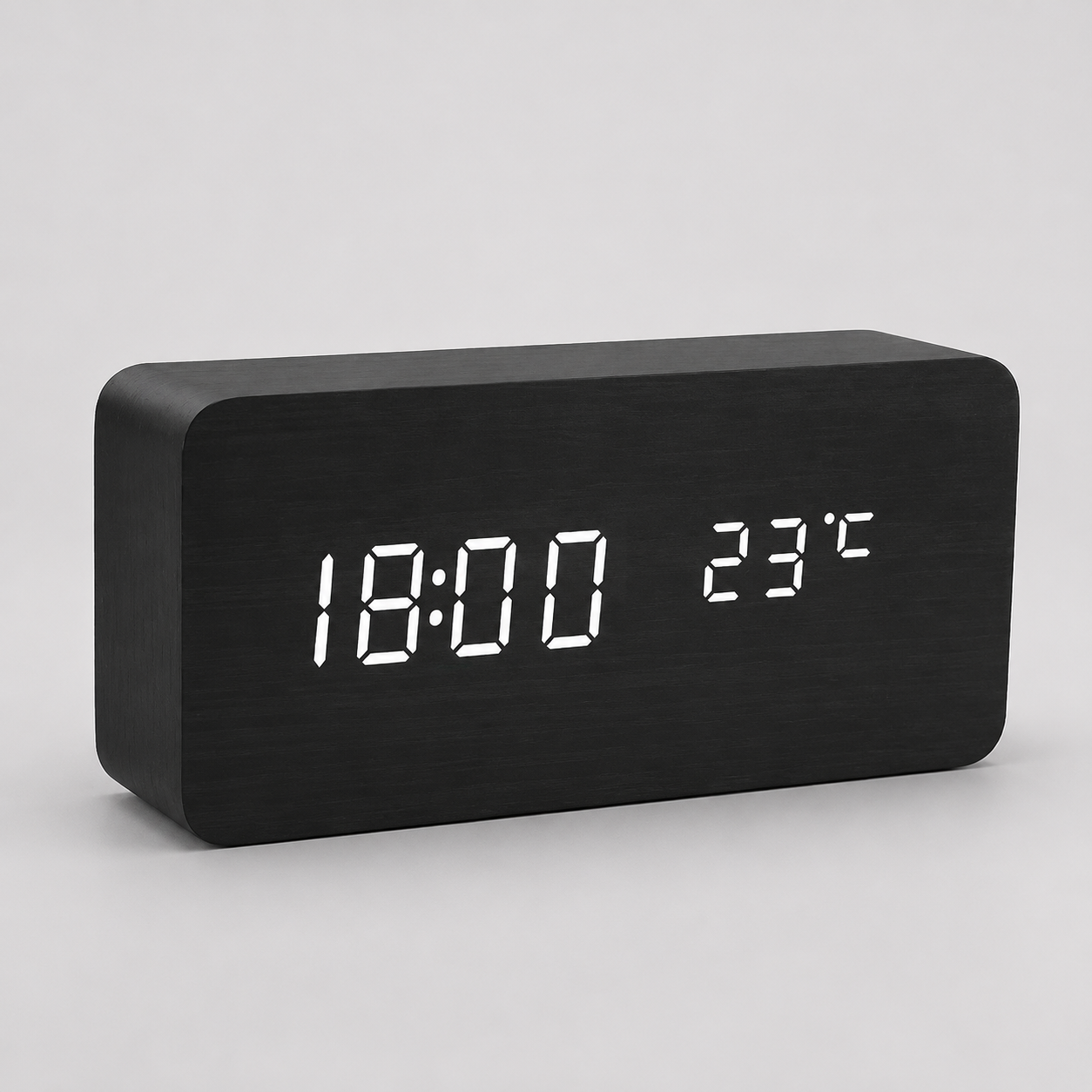 Black block LED alarm clock on a neutral gray studio background
