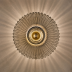 Front view of smoked gray ribbed glass wall sconce with radial light