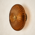 Cognac brown ribbed glass wall sconce on an ivory plaster wall