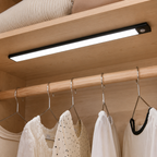 Black wireless motion sensor LED bar installed beneath a maple closet shelf